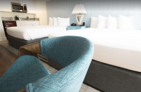 Blue chair with two beds and small kitchen in bright room