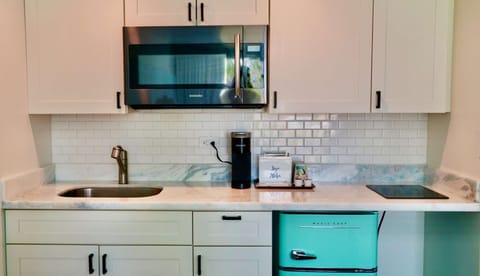 Bright kitchenette with microwave, sink, mini fridge, and stove