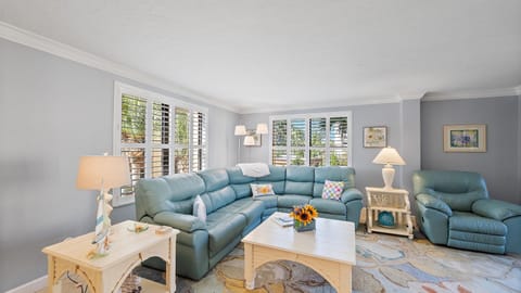 Settle into this spacious living room where comfort meets coastal charm - sink into the plush sectional sofa and enjoy the natural light streaming through plantation shutters.