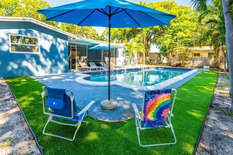 Relax in style by the pool with vibrant seating, lush artificial turf, and shady umbrellas—your perfect vacation rental escape awaits!