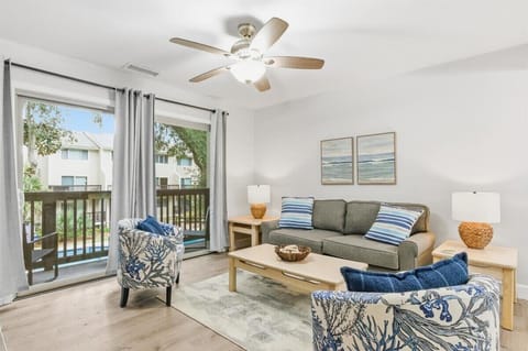 Bright coastal living room with balcony views, smart TV, and comfy seating.