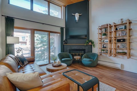 A stunning open living space featuring dramatic vaulted ceilings, designer décor, and floor-to-ceiling windows that fill the room with mountain sunlight.