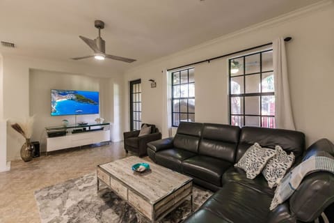 Large and open living area with leather section and wall mounted TV.