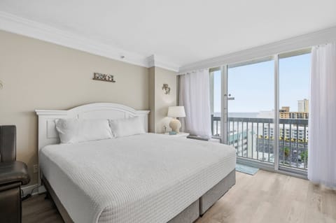Bright, coastal bedroom featuring a plush king bed and private balcony with ocean views. Wake up to fresh sea air and unwind in comfort—perfect for a relaxing beach stay just steps from the shore.