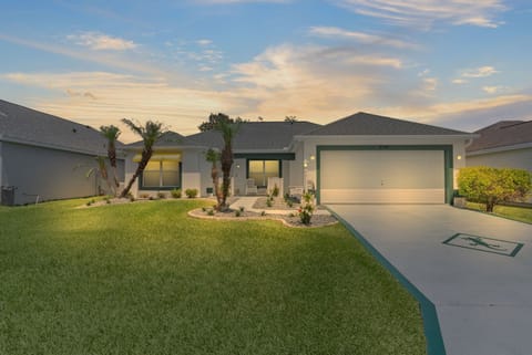 Modern single-story home with tropical landscaping and spacious driveway in peaceful residential neighborhood.