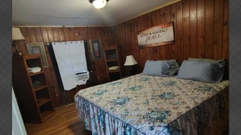 Bedroom with large bed, window AC, and shelving