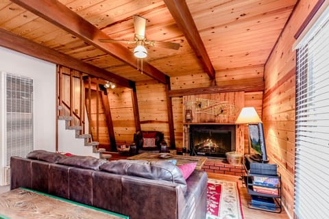 Cozy rustic living room with wood beams, leather sofa, and wood burning fireplace
