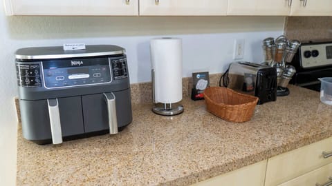Ninja Air Fryer Ready
Ninja dual-basket air fryer sits proudly on granite counters with toaster, paper towels, and spices nearby. Whip up crispy fries or wings effortlessly—modern cooking made simple for your vacation meals!