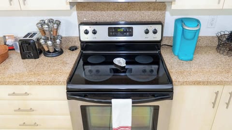 Fully Equipped Cooktop Range
Shiny glass cooktop with digital controls, stainless oven, and utensil drawer make meal prep a breeze on granite counters. Towel-ready beside fridge—whip up feasts for your beach crew with ease!