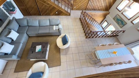 Relax and connect in this open, light-filled living dining area, featuring a plush sectional, inviting armchairs, and a spacious table for group meals. The dramatic wood finishes and soaring stairways create a striking, unforgettable gathering space.