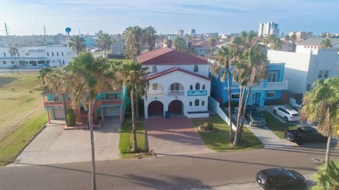 Classic coastal getaway with palm-lined curb appeal, double balconies, and spacious design. The inviting facade, charming arches, and vibrant tropical surroundings create the ideal setting for a relaxing beach vacation in the heart of the action.
