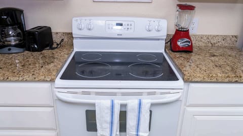 Modern Electric Range Setup
Sleek smooth-top electric stove with digital controls shines on granite amid toaster, blender, coffee maker. Blue towels hang ready; whip up breakfast or dinners easily in this fully equipped beach kitchen.

