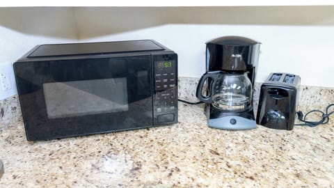 Breakfast Appliance Corner
Black microwave, drip coffee maker, and toaster perch ready on granite for quick mornings. Plug into vacation mode with fresh brews and toast—fuel up for beach adventures from your well-stocked kitchenette.