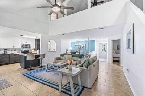 Bright living room w/ soaring ceilings, plush seating & large windows filling the space w/ natural light