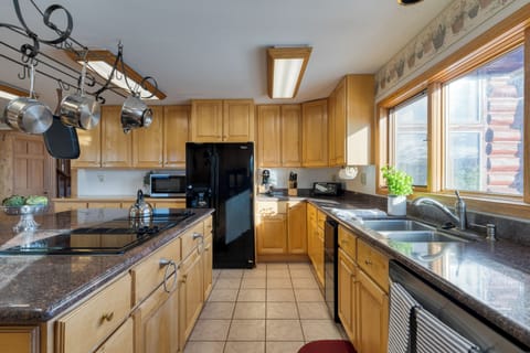 Kitchen showing dark appliances, light wood cabinets, and ample counter space.