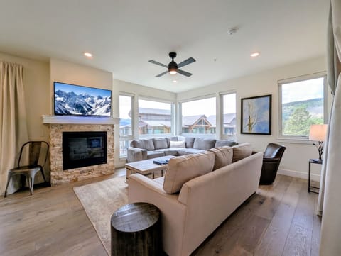 Sink into plush sofas and let your gaze wander through expansive windows to rolling green hills, while the cozy fireplace and modern comforts wrap you in relaxation.