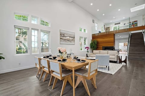 Dining room — 8-seat wooden table beneath vaulted ceiling with garden windows