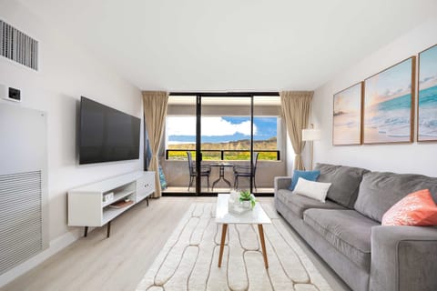 Unwind in style in your bright, modern living space featuring a 65" smart TV, coastal accents, and seamless access to a private, scenic balcony.