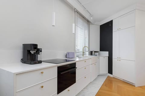 Sleek kitchen with white cabinetry, wooden accents, and integrated appliances.