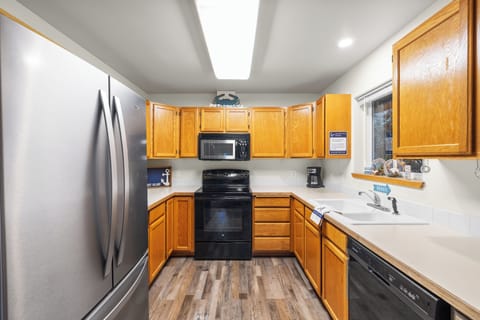 Kitchen with wood cabinets, black appliances, and a stainless steel refrigerator.
