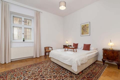Spacious bedroom with a comfortable double bed and classic wooden furniture. Bright interior with high ceilings creates a calm and elegant atmosphere.
