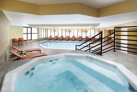 Indoor hot tub with seating and pool area nearby