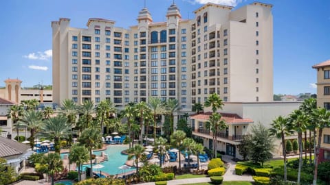 Poolside view with tall resort building and blue lounge chairs
