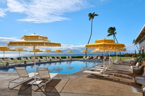 Pool deck with yellow umbrellas and lounge chairs facing the sea