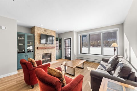 Cozy up in your spacious living room with a crackling fireplace, comfortable seating, and stunning lake views through large windows.
