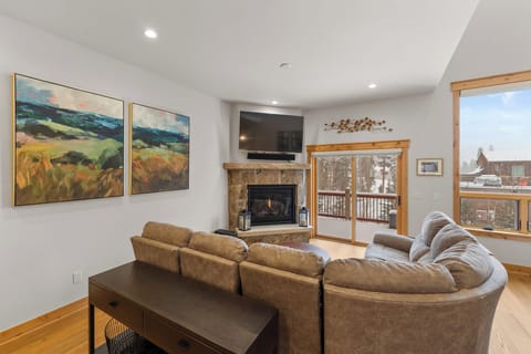 Sink into plush seating by your crackling fireplace, watching snow fall through panoramic windows in this cozy mountain retreat.