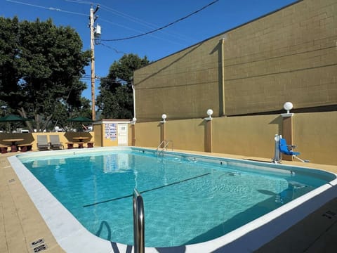 Pool with chairs and fence along the yellow wall