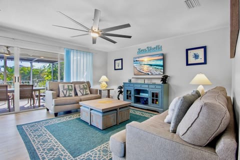 Relax in your coastal-themed living room with comfy seating, ceiling fan, and TV entertainment opening to your private balcony.