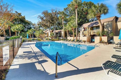 Tropical resort-style pool area with palm trees and comfortable lounging spaces for your perfect sunny getaway.