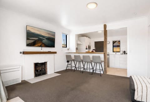 Light-filled living space with fireplace, mountain artwork/TV, and bar seating  cosy and stylish