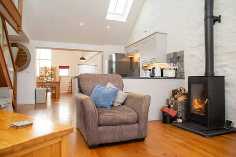 Armchair with blue cushion in open-plan living room beside wood-burning stove