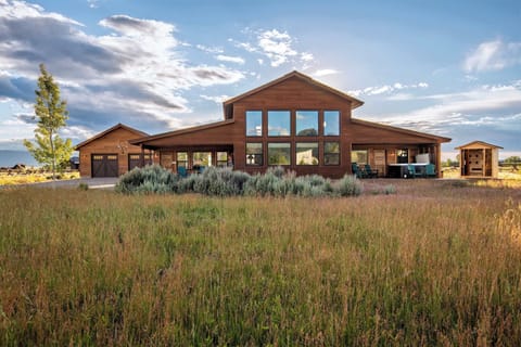 Wide-open exterior — the home set into the Teton Valley landscape with sage, sky, and mountain views in every direction