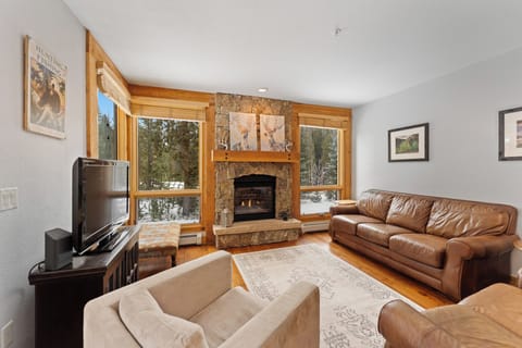 Cozy up in your mountain retreat with crackling fireplace, plush leather seating, and forest views through large windows.