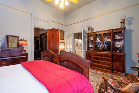 Bedroom view showcasing the carved wood bed, period cabinetry, and rich textiles.