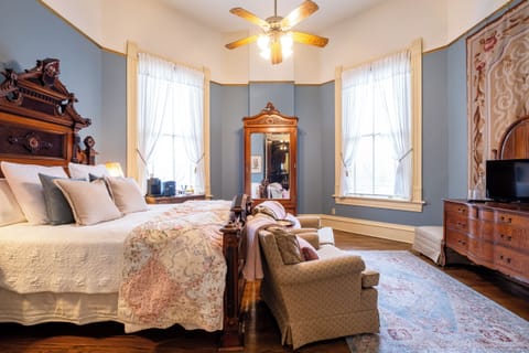 Bright and airy bedroom with tall windows, vintage décor, and original hardwood floors.