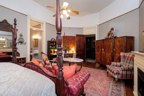 Four-poster king bed, antique wardrobe, hardwood floors, and classic Victorian furnishings.