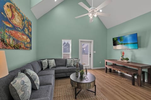 Relax in your spacious living room featuring vaulted ceilings, comfortable sectional seating, and tropical artwork that sets the perfect vacation mood.