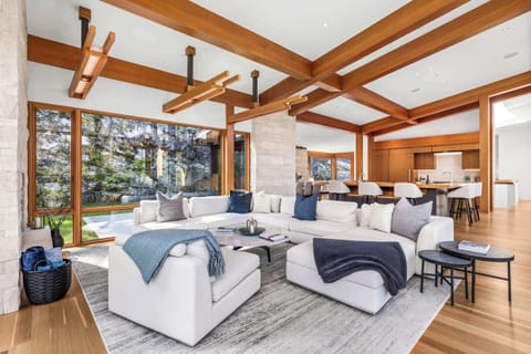 Open-concept living area framed by warm wood beams & expansive windows that bring the outdoors in.