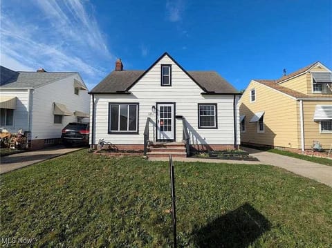 Front view of the charming home w/ small porch & grassy yard