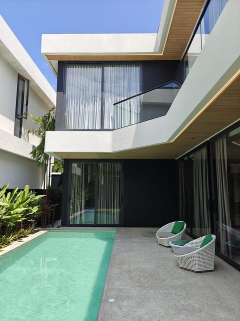 Modern villa exterior with sleek architectural lines, large windows, and a private pool surrounded by tropical greenery.