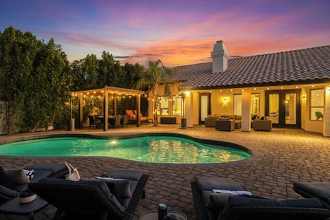 Sunset view of the backyard, highlighting the pool and lit gazebo
