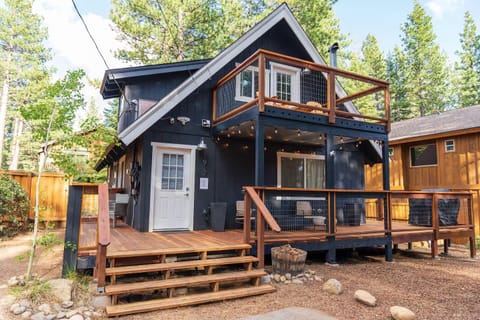 Charming cabin with multi-level deck where you'll unwind under twinkling lights, surrounded by towering pines and mountain serenity.