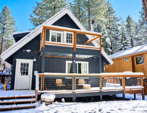 A charming snow-covered cabin retreat nestled among evergreen trees, featuring modern touches and spacious deck areas for mountain getaways.