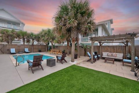 Your private oasis features a sparkling pool, covered lounge area, and tropical palms under dreamy sunset skies.