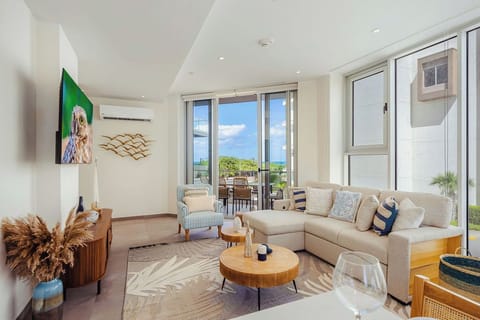 Unwind in your spacious, light-filled living room where elegant coastal décor meets comfort. Relax on the plush sofa and enjoy ocean breezes flowing through floor-to-ceiling doors that open to your private terrace.