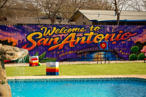 Resort-style backyard with pool, lawn games, and our colorful mural
